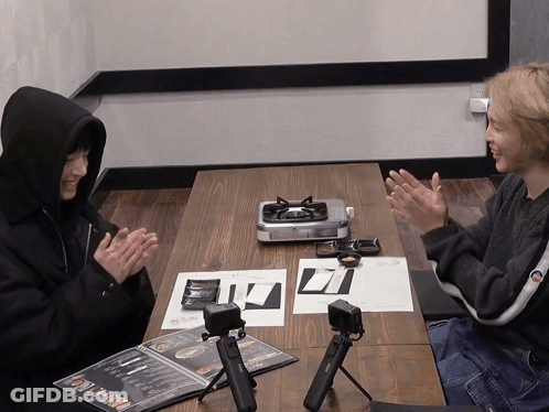 Two People Sitting At A Table With A Menu On It That Says ' Noodles ' On It GIF