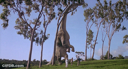 Two People Standing Before Giant Dinosaur GIF