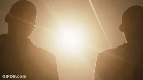Two People Standing Next To Each Other In Front Of A Bright Light GIF