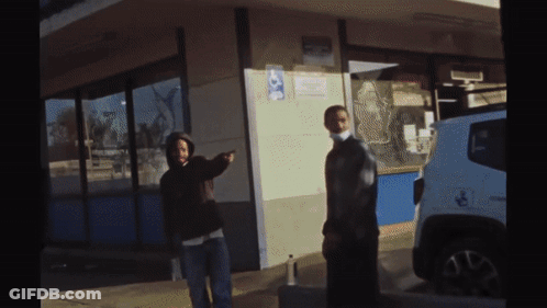 Two People Standing Outside Of A Building With A Handicap Sign On The Side GIF
