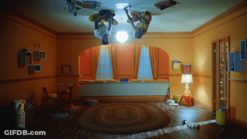 Two People Upside Down In Room With Lamp And Box Saying A GIF