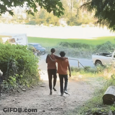 Two People Walking Down A Dirt Path With A White Truck Parked Behind Them That Says ' A ' On It GIF