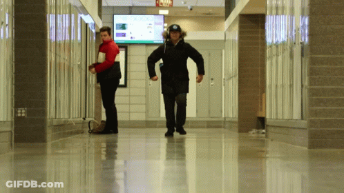 Two People Walking Down A Hallway With A Sign That Says Jojo GIF