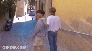 Two People Walking On Narrow Street With Motorcycle GIF