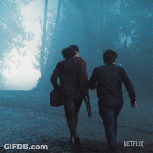 Two People Walking Through Foggy Forest GIF