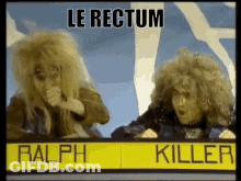 Two People With Sign Saying Le Rectum Ralph Killer GIF
