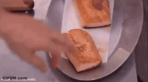 Two Pieces Of Bread Are Sitting On A Plate On A Table . GIF