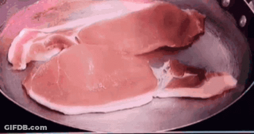 Two Pieces Of Raw Bacon Cooking In A Frying Pan GIF