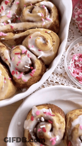 Two Plates Of Cinnamon Rolls With Icing And Sprinkles GIF