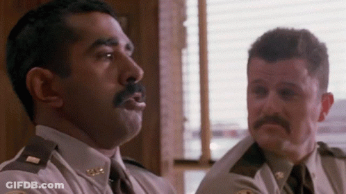 Two Police Officers Are Sitting Next To Each Other In A Room And Talking To Each Other . GIF