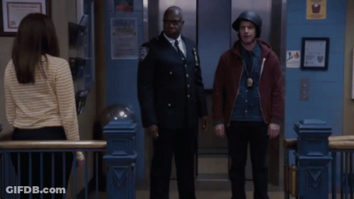 Two Police Officers Giving Each Other A Fist Bump In Front Of An Elevator GIF