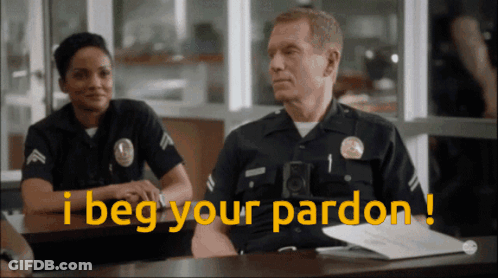 Two Police Officers Sitting At Desk Saying I Beg Your Pardon GIF