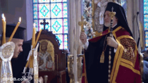 Two Priests Are Standing In Front Of A Stained Glass Window Holding Crosses And Candles GIF