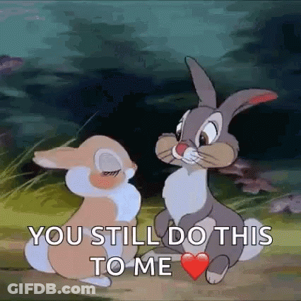 Two Rabbits Sitting With One Holding Heart In Mouth GIF