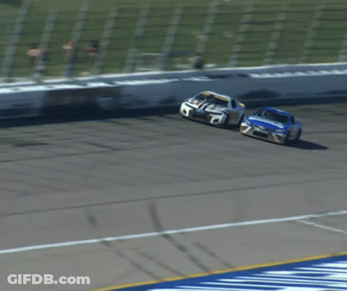 Two Race Cars Racing On Track With White Fence GIF