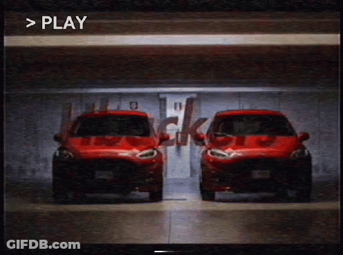 Two Red Cars Are Parked Next To Each Other In A Garage With The Word Play Visible In The Corner GIF