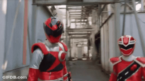Two Red Rangers Are Walking Down A Hallway GIF