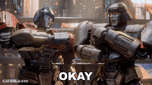 Two Robots Standing Together Saying Okay GIF