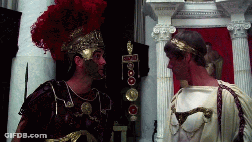 Two Roman Soldiers Standing Next To Each Other With A Sign That Says ' S.r.o.m. ' On It GIF