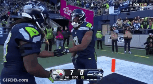 Two Seahawks Players Are Shaking Hands On The Field During A Fox NFL Game GIF