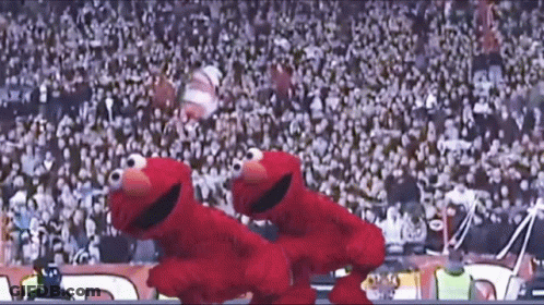 Two Sesame Street Characters Are Dancing In Front Of A Crowd At A Stadium GIF