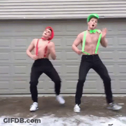 Two Shirtless Men Are Dancing In Front Of A Garage Door Wearing Suspenders And A Green Bow Tie . GIF