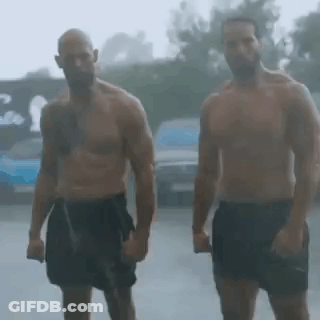 Two Shirtless Men Are Standing In The Rain Holding Hands . GIF
