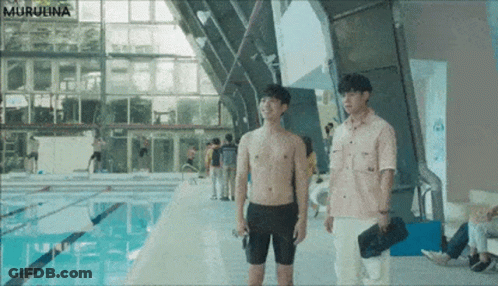 Two Shirtless Men Are Standing Next To A Swimming Pool GIF