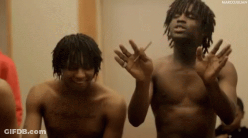 Two Shirtless Men Are Standing Next To Each Other And One Is Smoking A Cigarette GIF