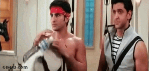 Two Shirtless Men Are Standing Next To Each Other In A Room . One Of The Men Is Wearing A Red Headband . GIF