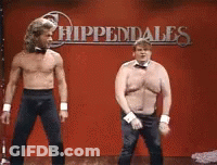 Two Shirtless Men Dancing In Front Of Hippendales Sign GIF