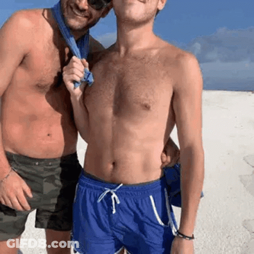 Two Shirtless Men On Beach One Holding Towel GIF