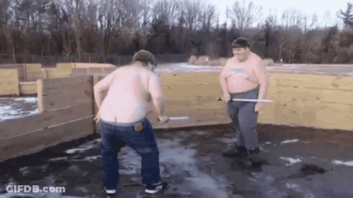 Two Shirtless Men With Swords At Wooden Fence GIF
