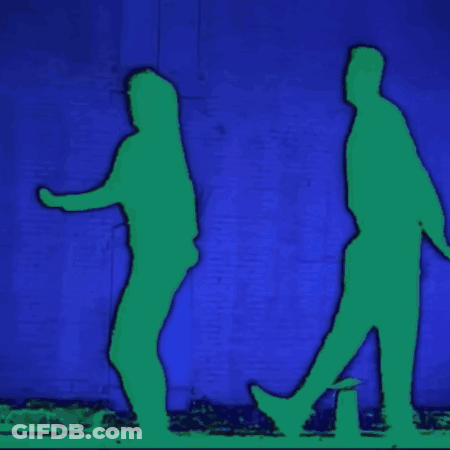 Two Silhouettes Of A Man And A Woman Walking In Front Of A Blue Wall GIF