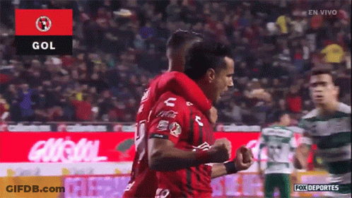 Two Soccer Players Are Celebrating A Goal In Front Of A Crowd GIF