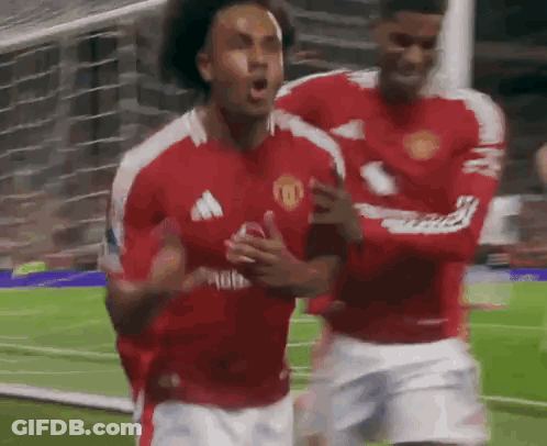 Two Soccer Players Are Celebrating A Goal On The Field . GIF