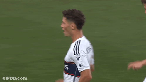 Two Soccer Players Are Celebrating A Goal On The Field While Sitting On The Ground . GIF