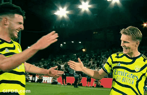 Two Soccer Players Are Giving Each Other A High Five On The Field GIF