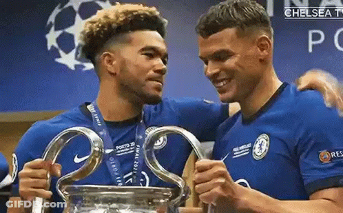 Two Soccer Players Are Holding A Trophy In A Locker Room . GIF