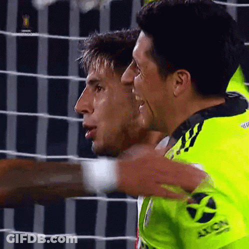 Two Soccer Players Are Hugging Each Other And One Has The Word Axion On His Sleeve GIF