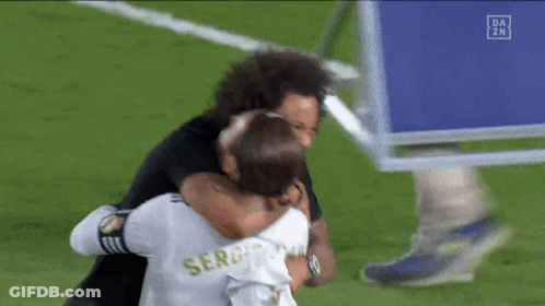 Two Soccer Players Are Hugging Each Other On A Field . GIF