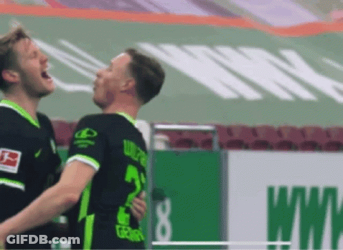 Two Soccer Players Are Hugging Each Other On A Field . GIF