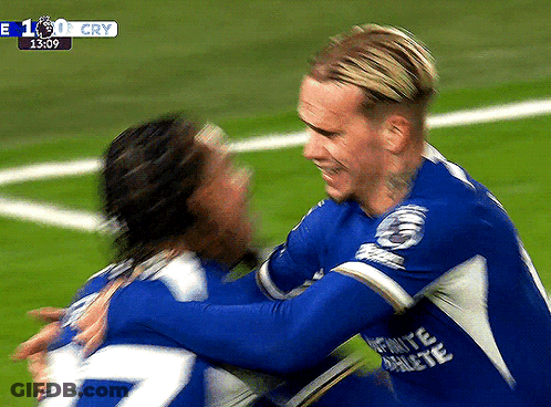 Two Soccer Players Are Hugging Each Other On A Field With A Score Of 1:0 GIF