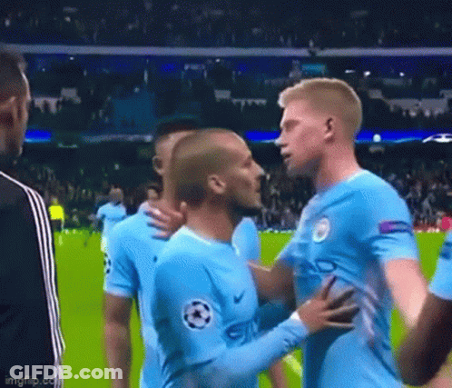 Two Soccer Players Are Hugging Each Other On The Field . GIF