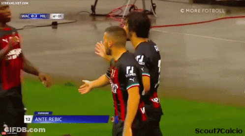 Two Soccer Players Are Hugging Each Other On The Field . GIF