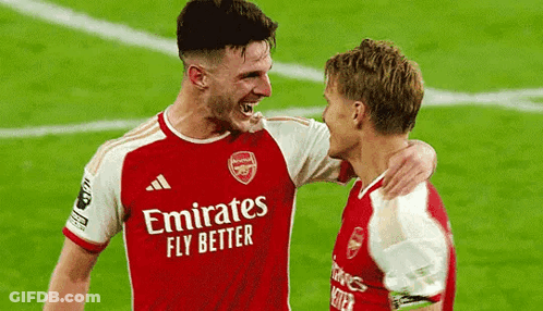 Two Soccer Players Are Hugging Each Other On The Field . GIF