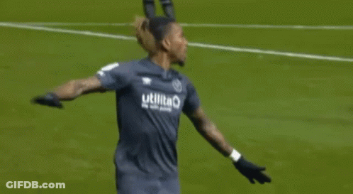 Two Soccer Players Are Hugging Each Other On The Field . GIF