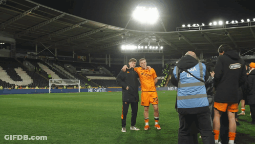 Two Soccer Players Are Posing For A Picture On A Field With A No Sweat Advertisement In The Background GIF