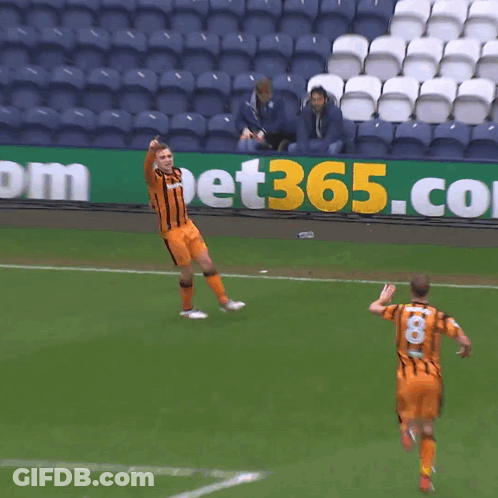 Two Soccer Players Are Running On A Field In Front Of A Sign That Says Bet365 GIF