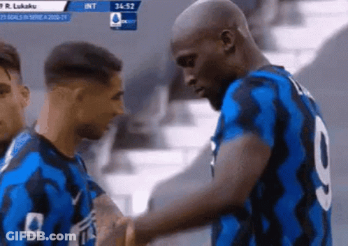 Two Soccer Players Are Shaking Hands In A Stadium . GIF